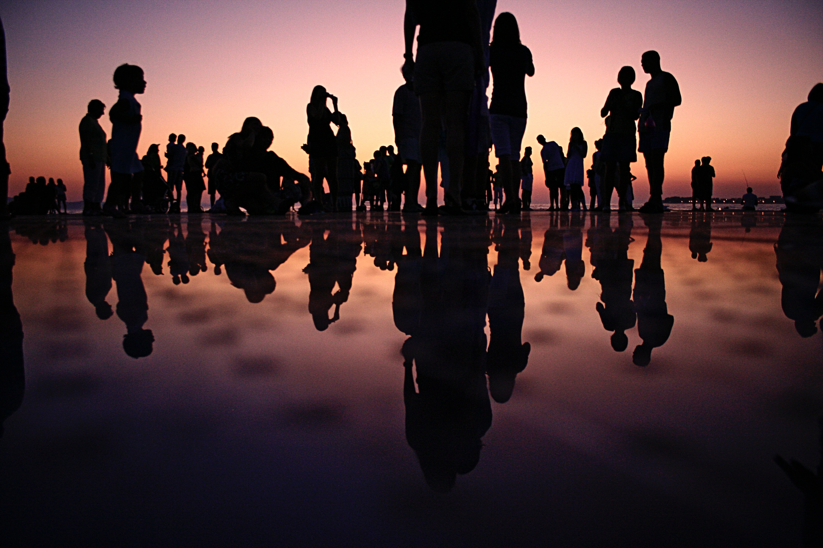 Silhouetted people standing on a mirrored surface