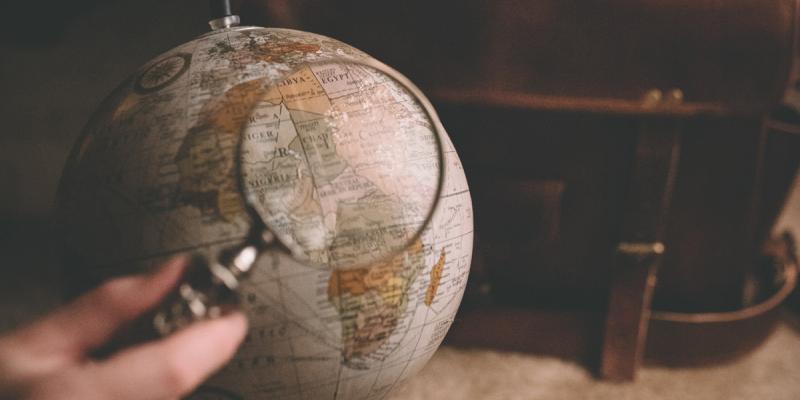 Magnifying glass above a globe. Photo by Clay Banks on Unsplash.